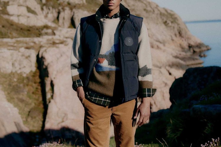 a model in a sweater and best and corduroy against a rocky background