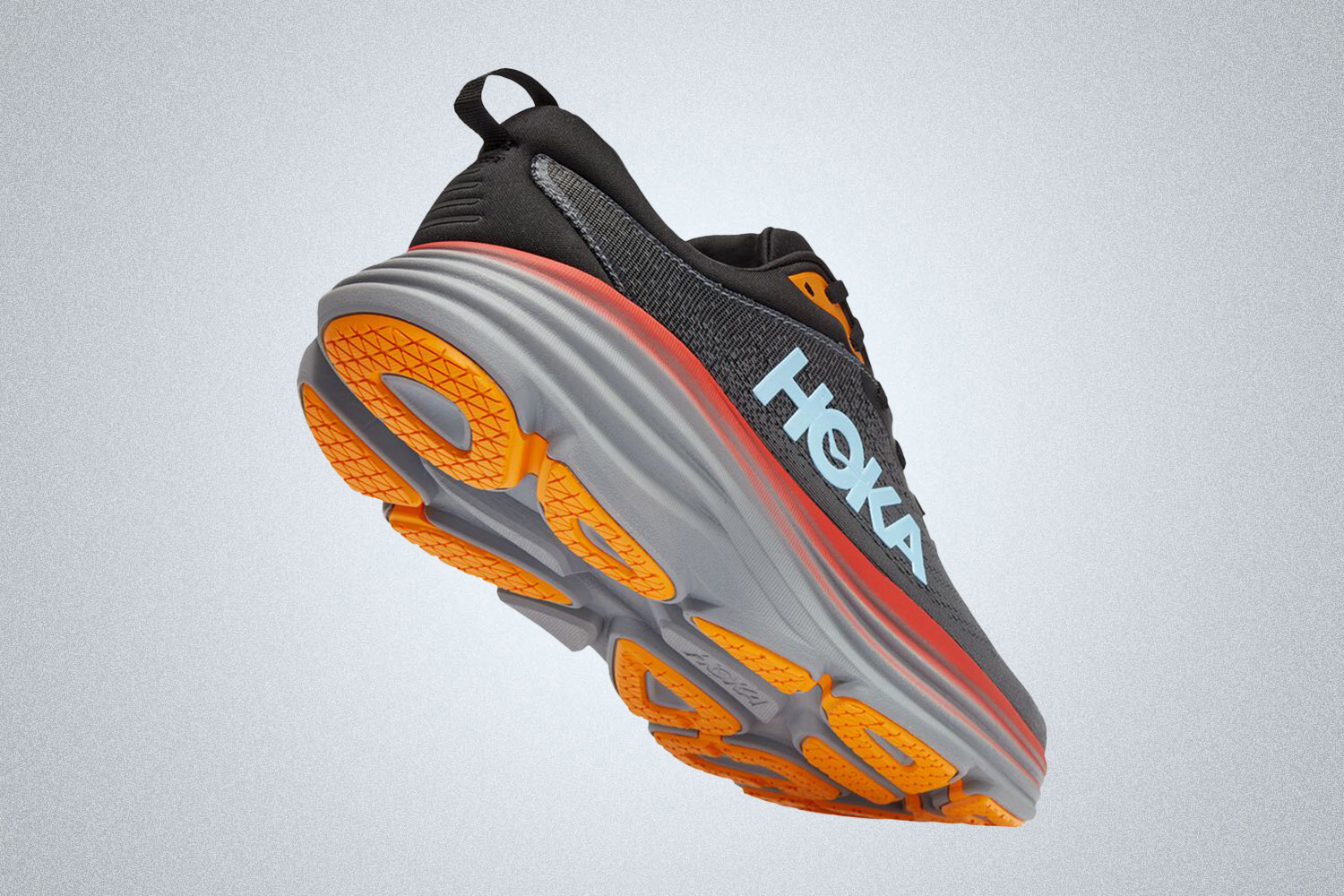 a black, grey and orange cushioned running shoe from Hoka on a grey background
