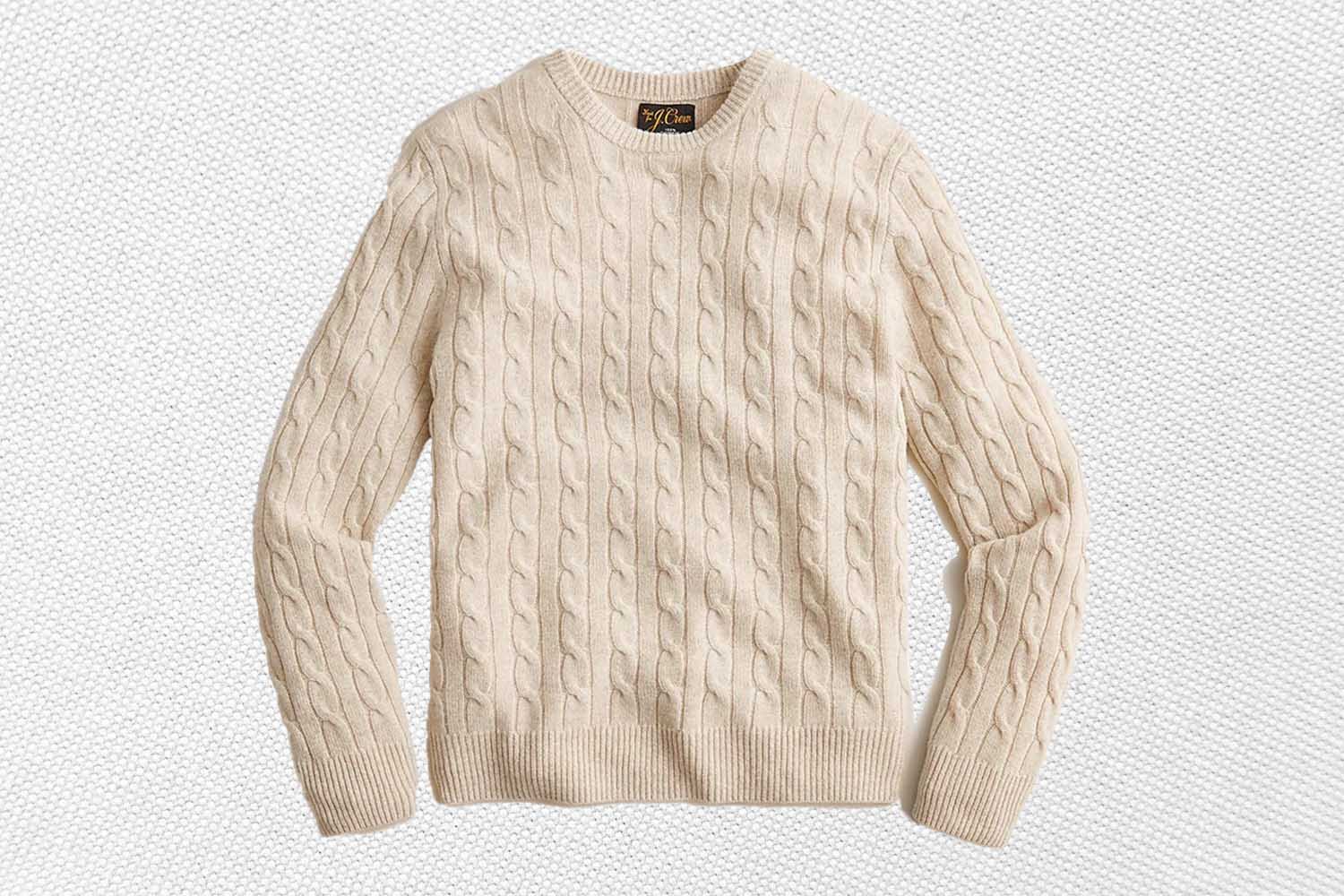 a white cable-knit cashmere sweater from J.Crew on a textured white background