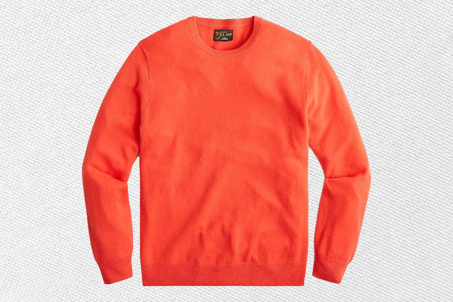 an orange cashmere sweater  from J.Crew on a textured white background