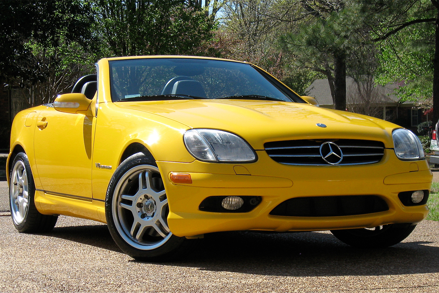 A yellow Mercedes-Benz SLK 32 AMG sitting in a driveway. It's considered a modern classic car, but it shares a platform with something more interesting.