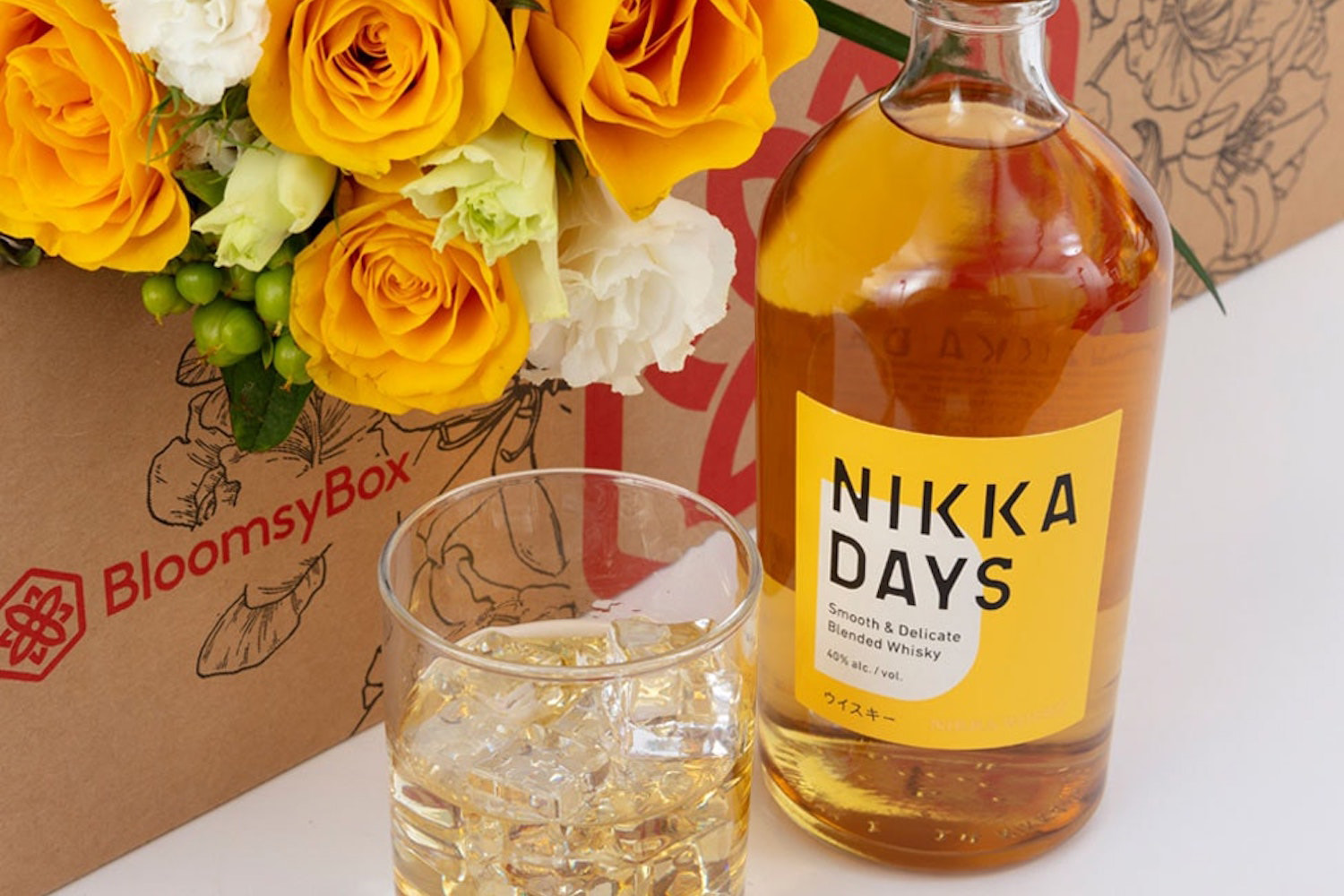 a amber Nikka whiskey bottle, glass, and box of flowers