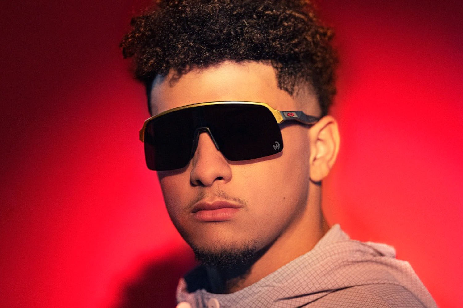 NFL quarterback Patrikc Mahomes wearing Oakley sunglasses against a red background