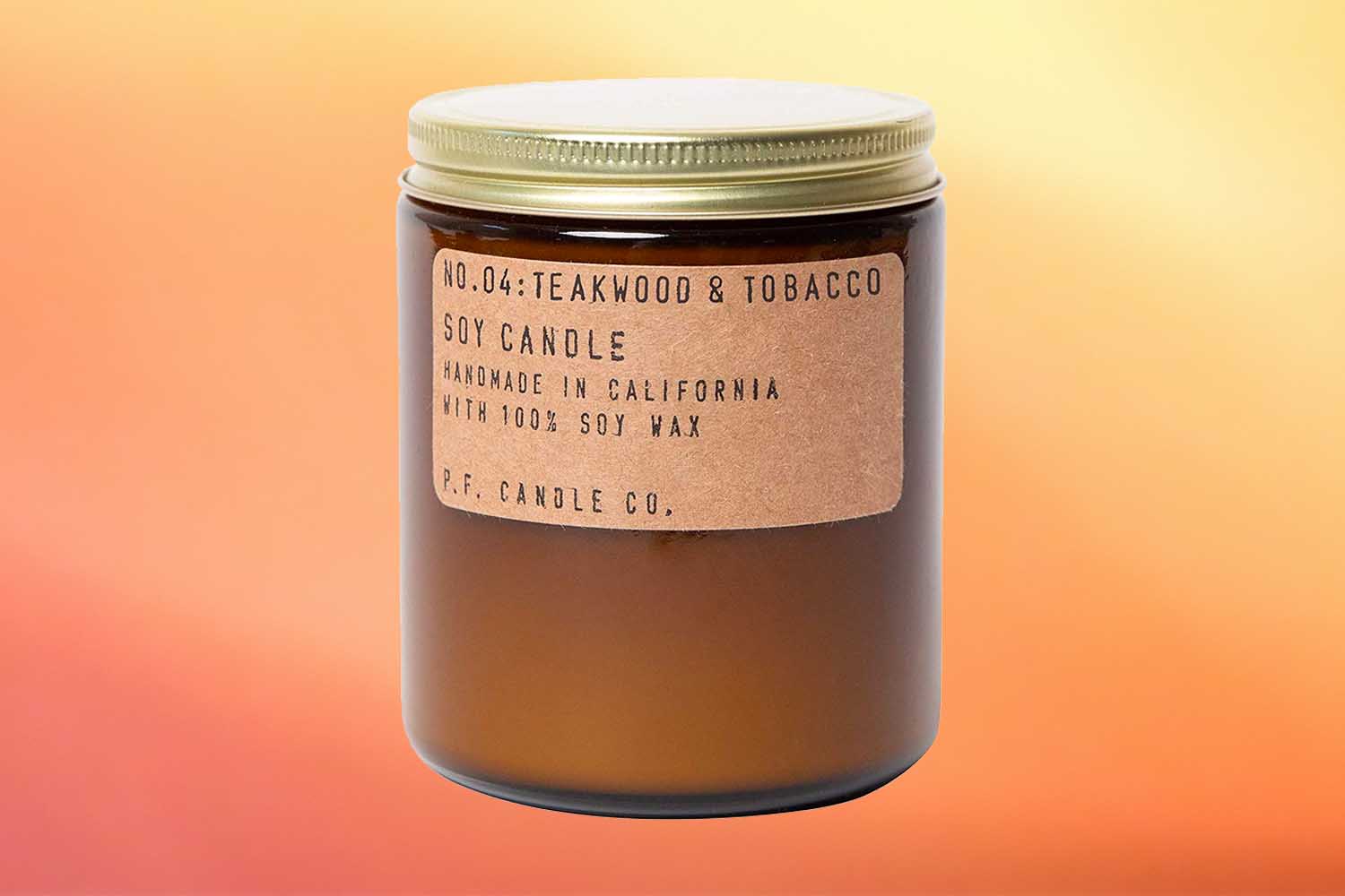 P.F. Candle Co. Teakwood and Tobacco Candlene of the best fall candles for 2022 on an orange background