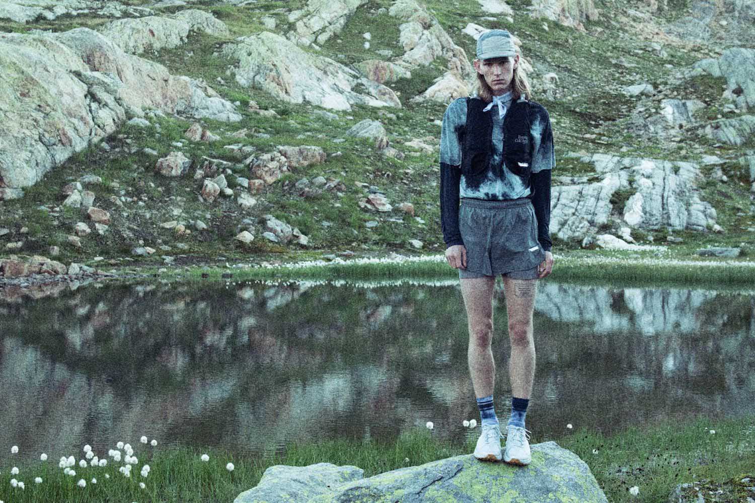 a model standing on a rock in a pond in Satisfy Running Clothing