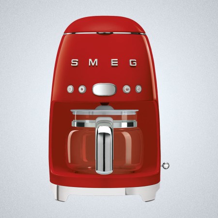 A red Smeg Drip Filter Coffee Machine on a gray background