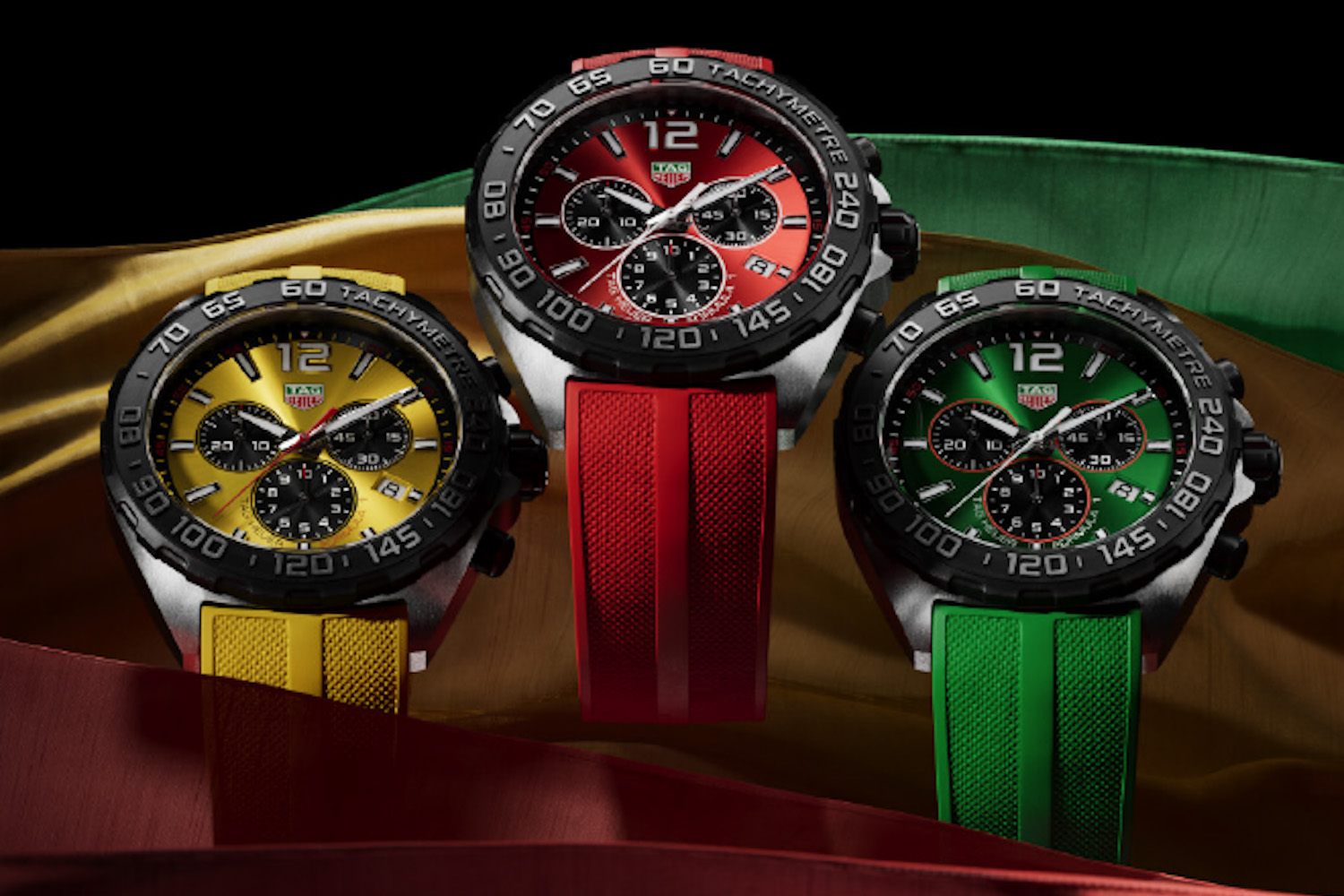 a trio of TAG Heuer F1 chronographs with yellow, red and green faces on a black background