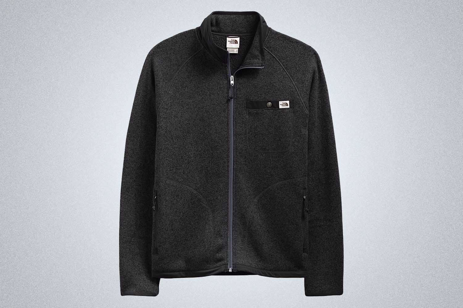 a black fleece jacket from The North Face on a grey background