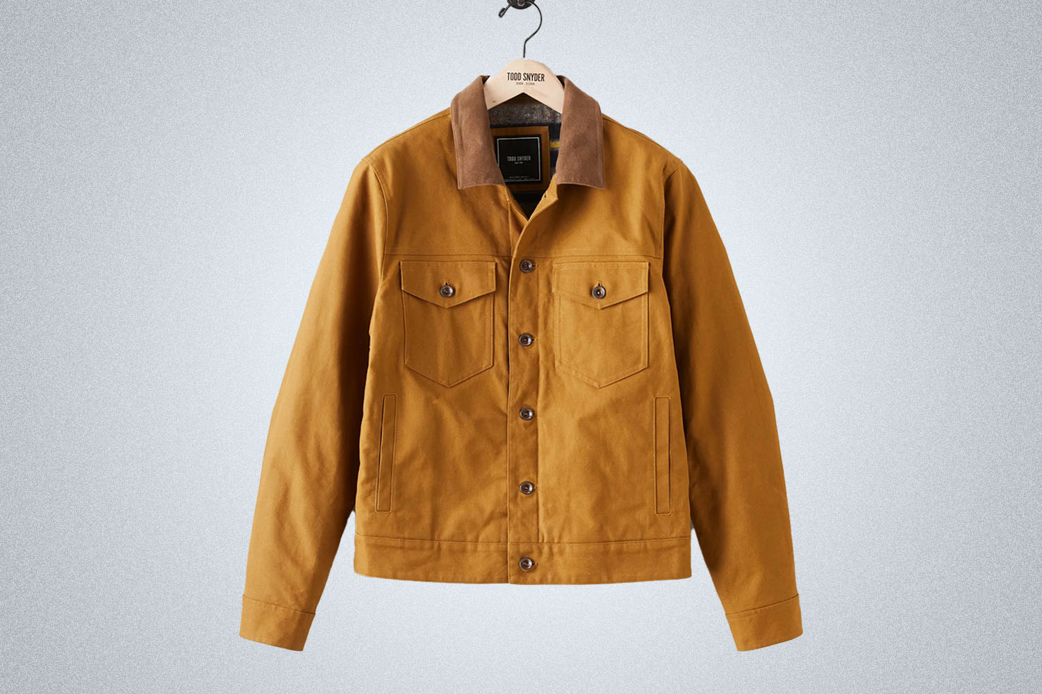 A tan waxed trucker jacket from Todd Snyder on a grey background