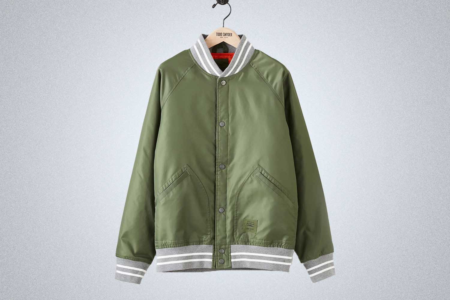 a green bomber jacket from Todd Snyder on a grey background