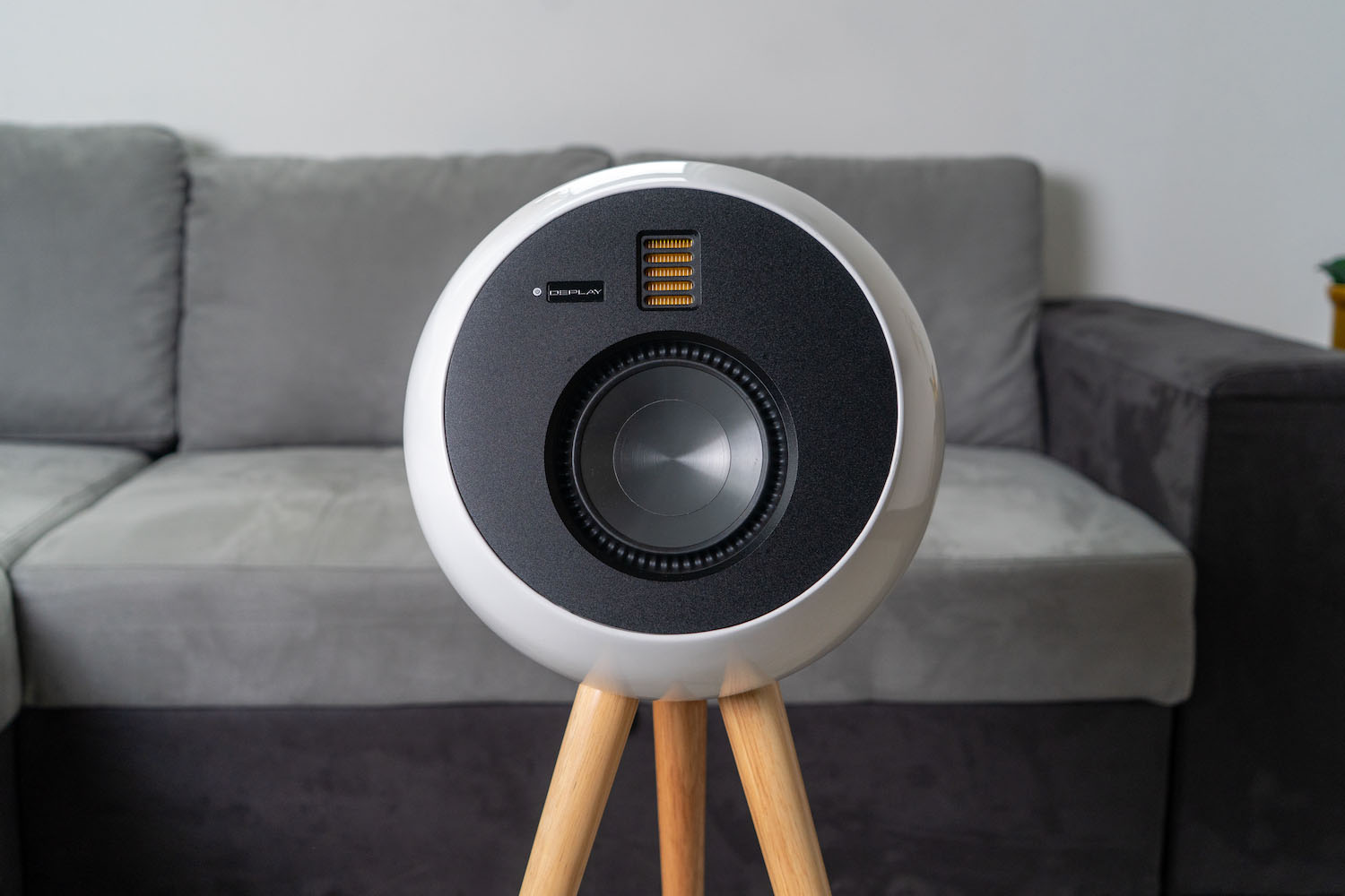 a white and black circular standing speaker against a living room background