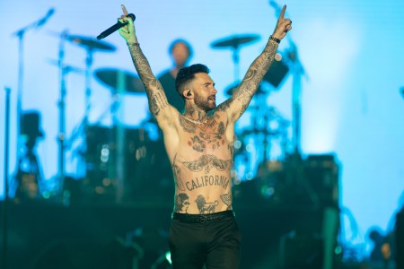 Adam Levine shirtless and on-stage with his arms raised