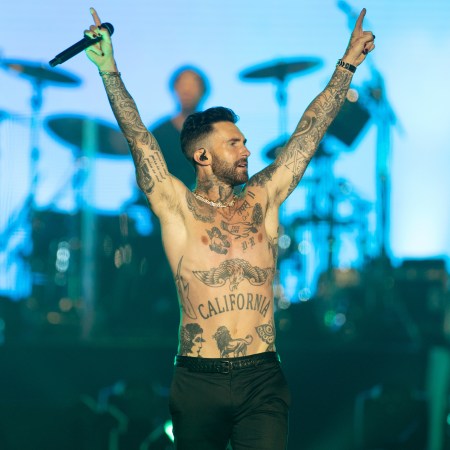 Adam Levine shirtless and on-stage with his arms raised