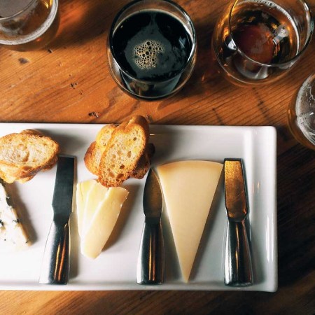 Directly Above Shot Of Cheese And Bread In Plate By Beer Glasses On Table. Beer and cheese can make for a better pairing than wine and cheese, according to some experts.