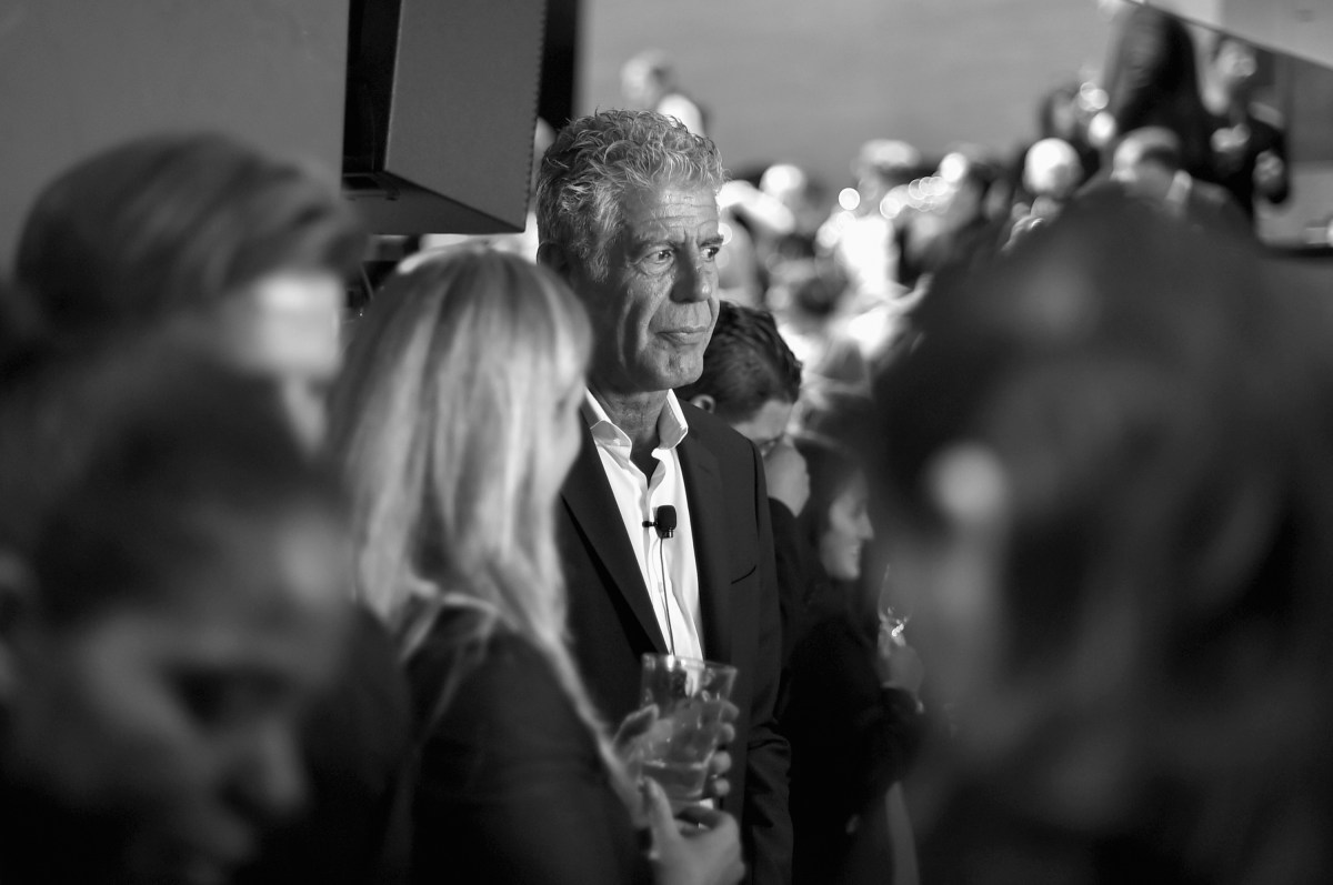 Anthony Bourdain standing in a crowd at a screening looking pensive.