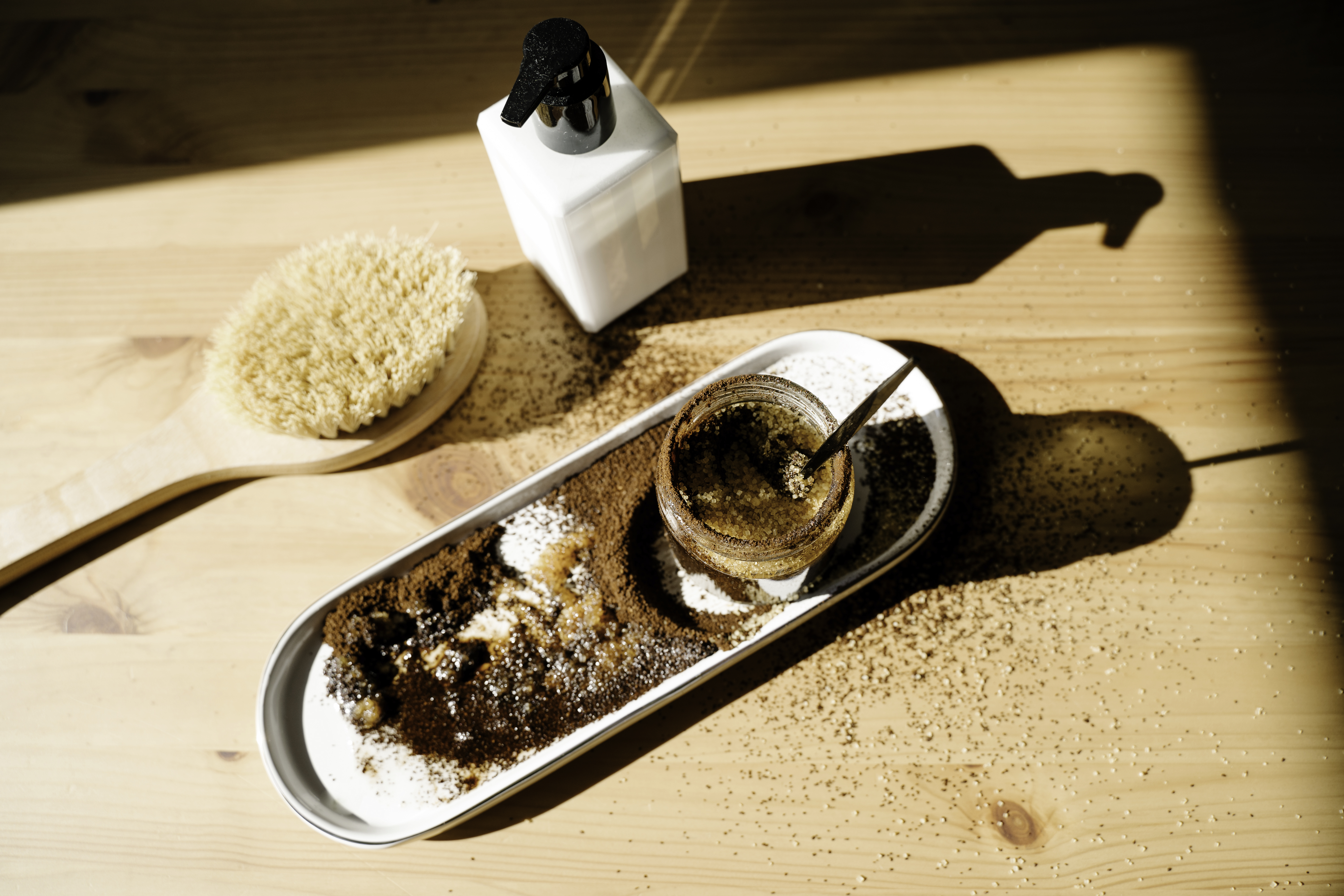The ingredients necessary for a homemade coffee scrub, laid out on a wooden tables.