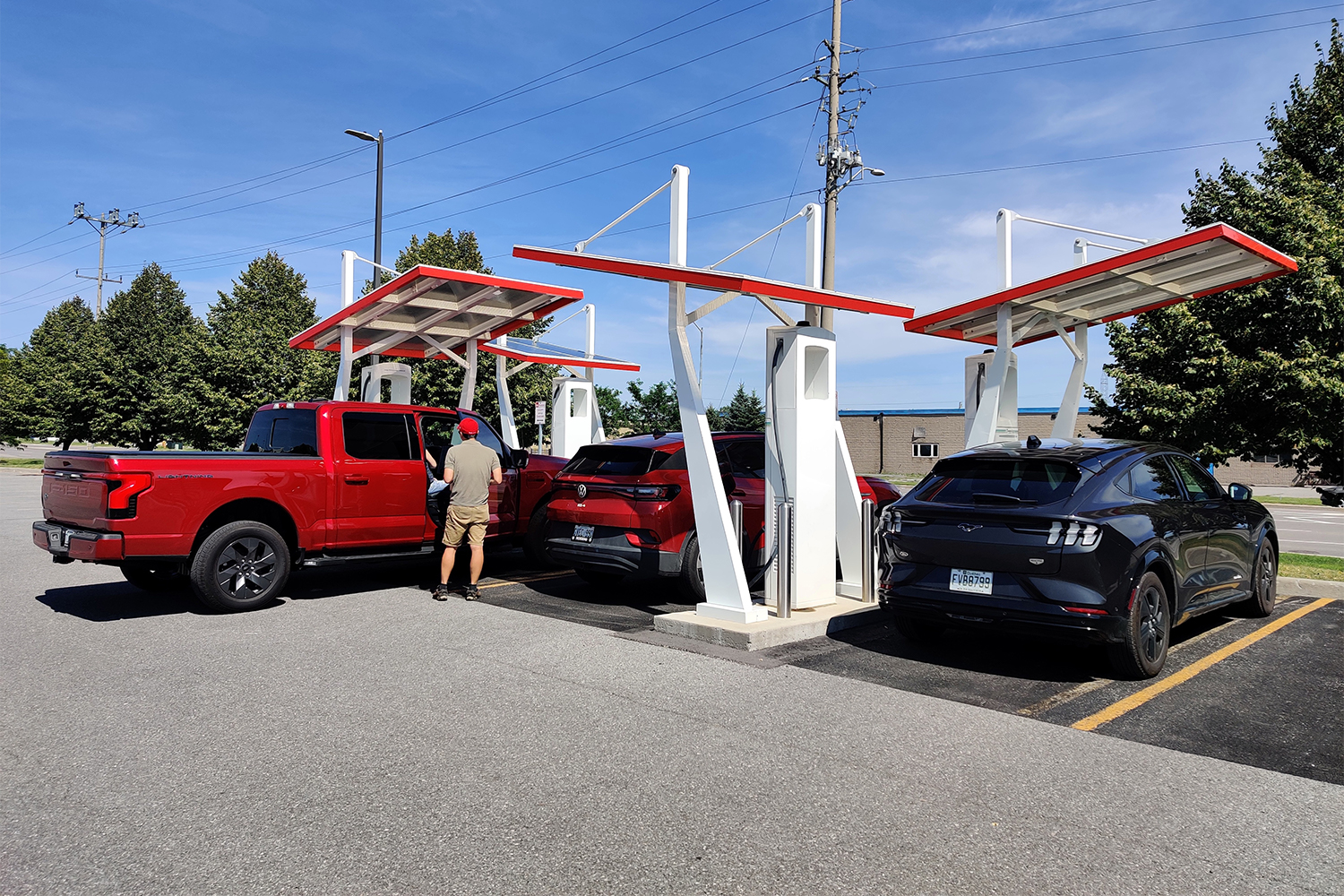 An electric truck and two electric SUVS charging at an Electrify Canada station in Ontario