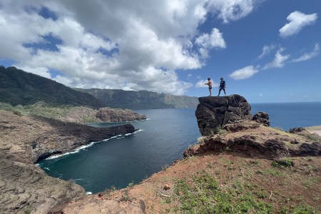 Two men standing on Virgin Rock in French Polynesia's Marquesas Islands