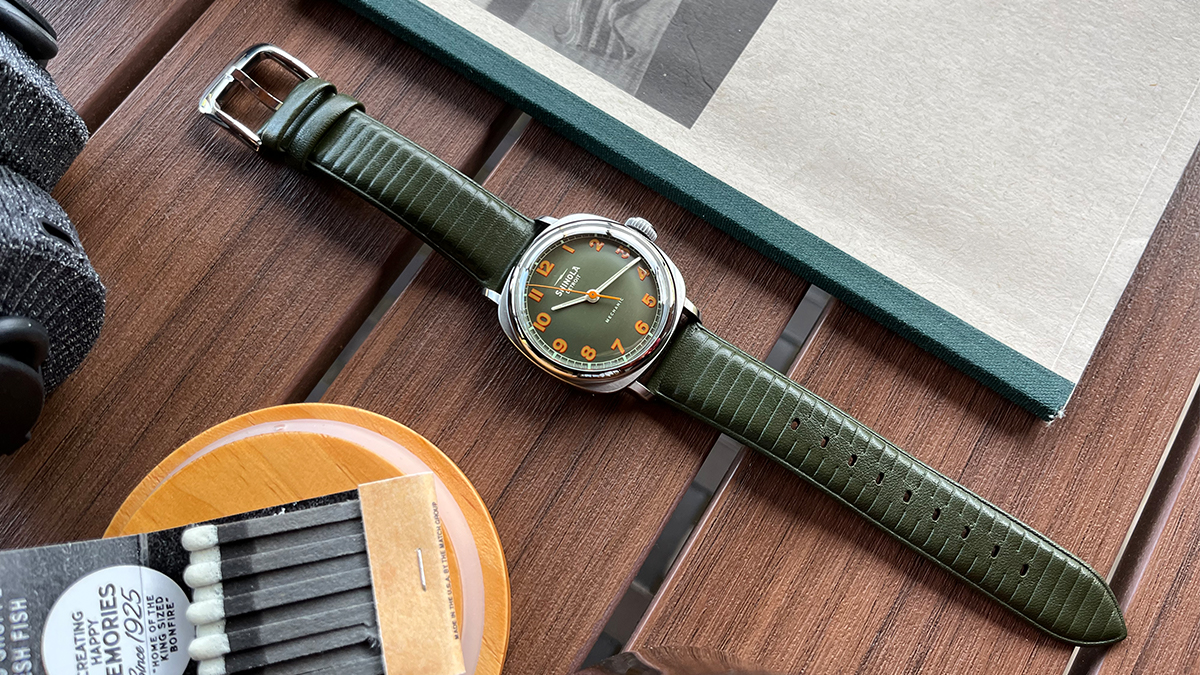 The Shinola Mechanic hand-wound watch in olive green sitting on a table. We tested and reviewed the new timepiece