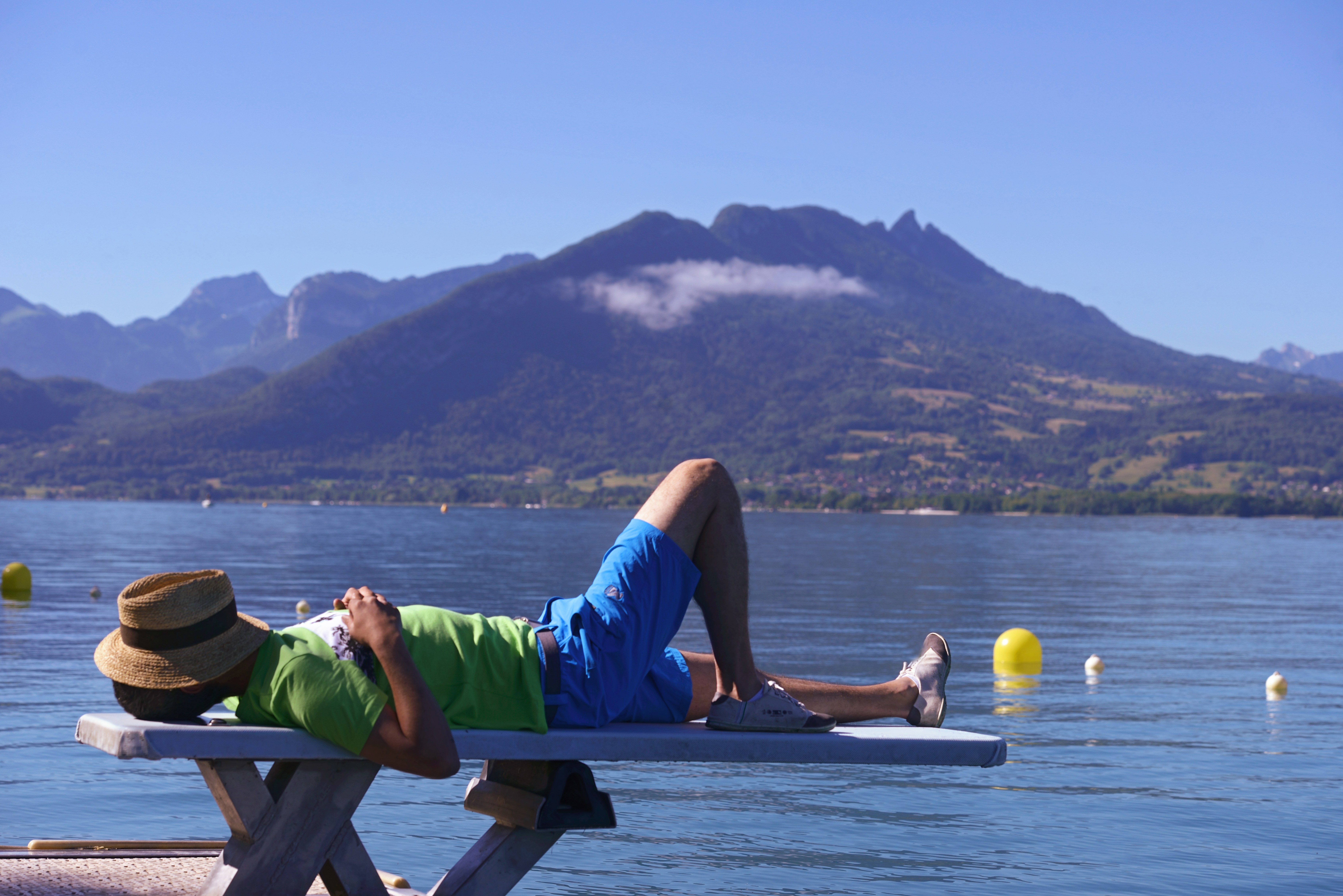 A man sleeping on a diving board with a hat pulled low over his face.