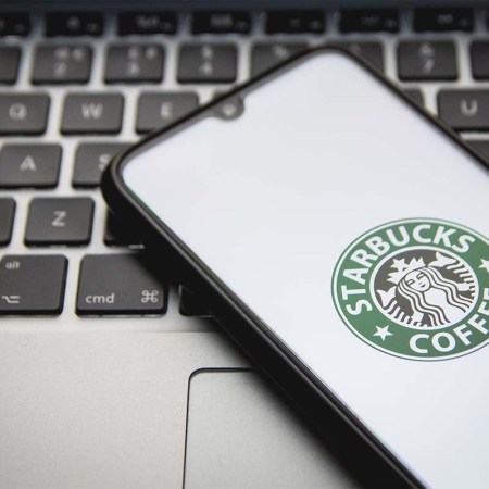 A photo illustration of a Starbucks logo seen displayed on a smartphone screen. Starbucks is introducing a web3-based loyalty program called Odyssey.