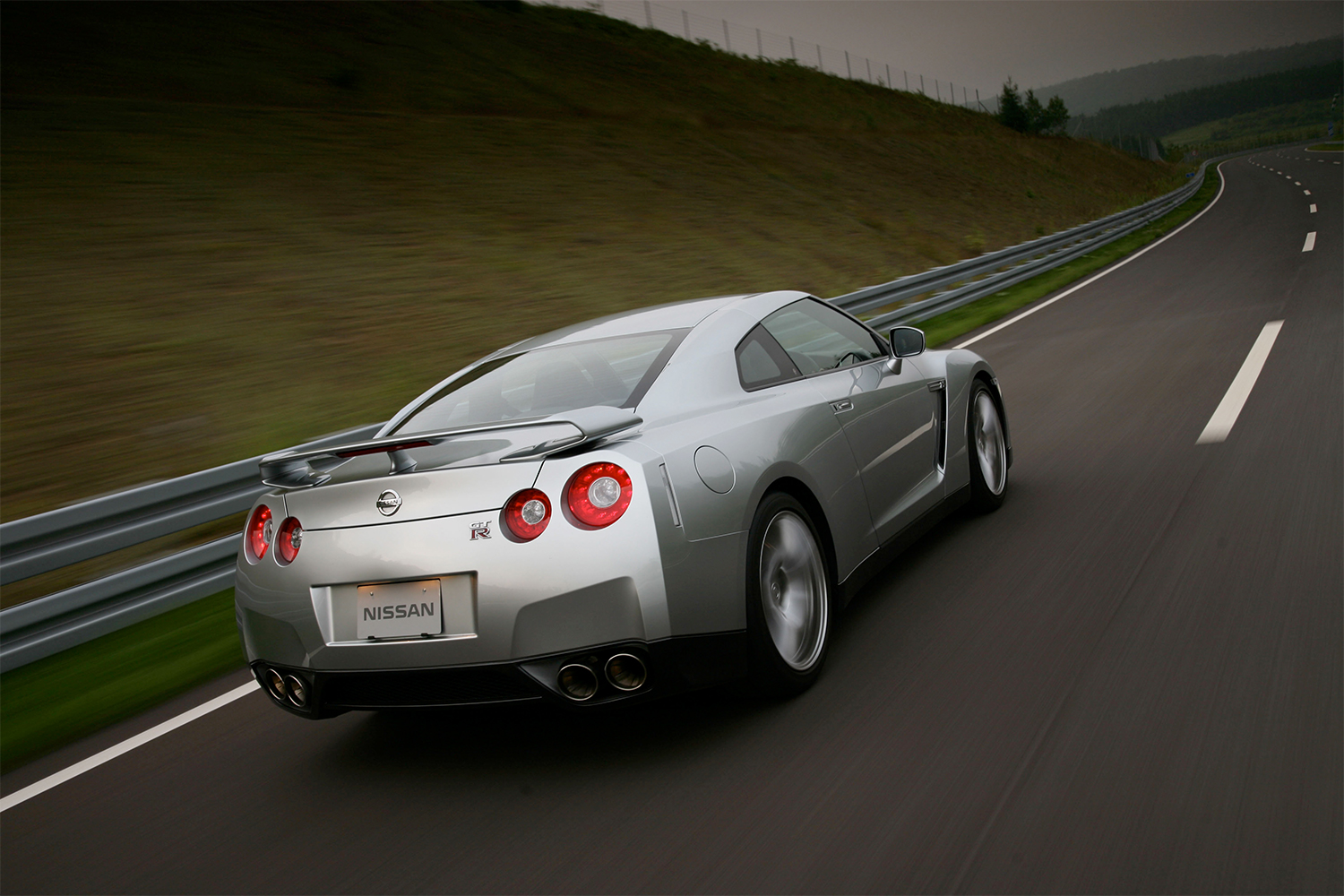 A 2009 Nissan GT-R R35 driving down a road, photographed from the rear
