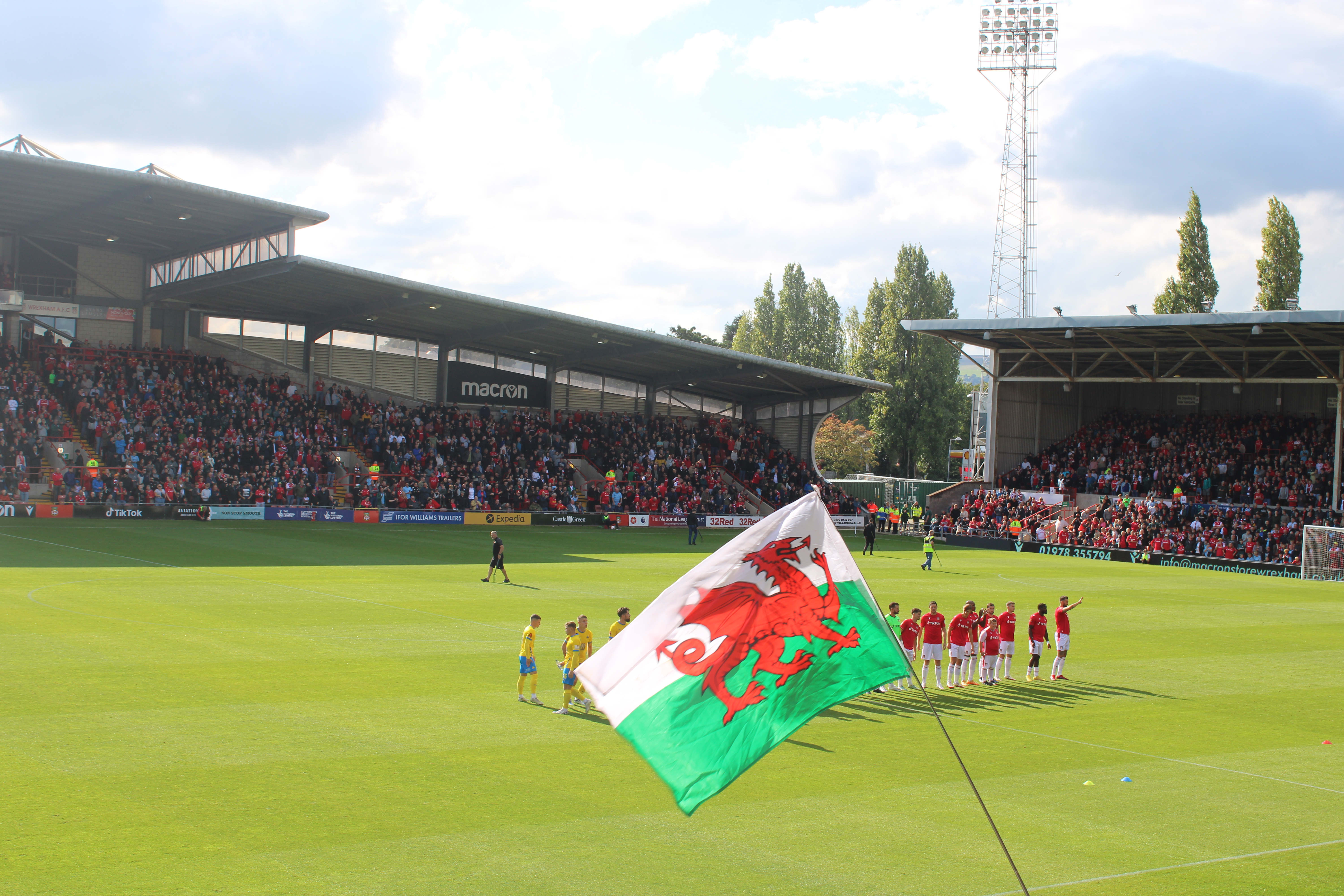 Wrexham soccer players on the pitch with a flag in front of them.