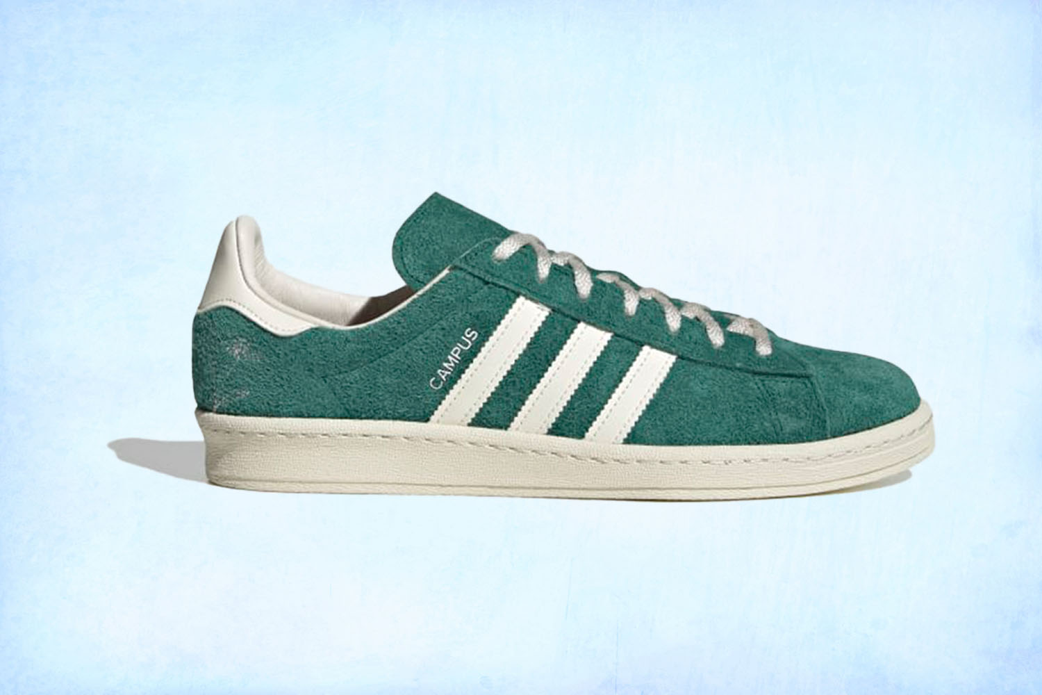 a pair of green Adidas campus sneakers on a light blue background