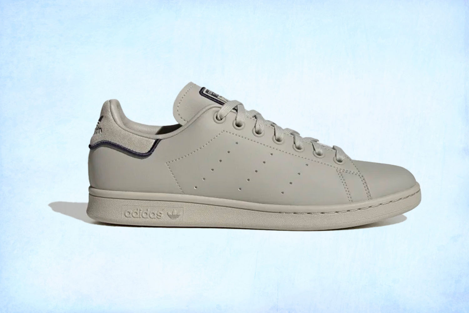 a tan Adidas Stan Smith sneaker on a light blue background