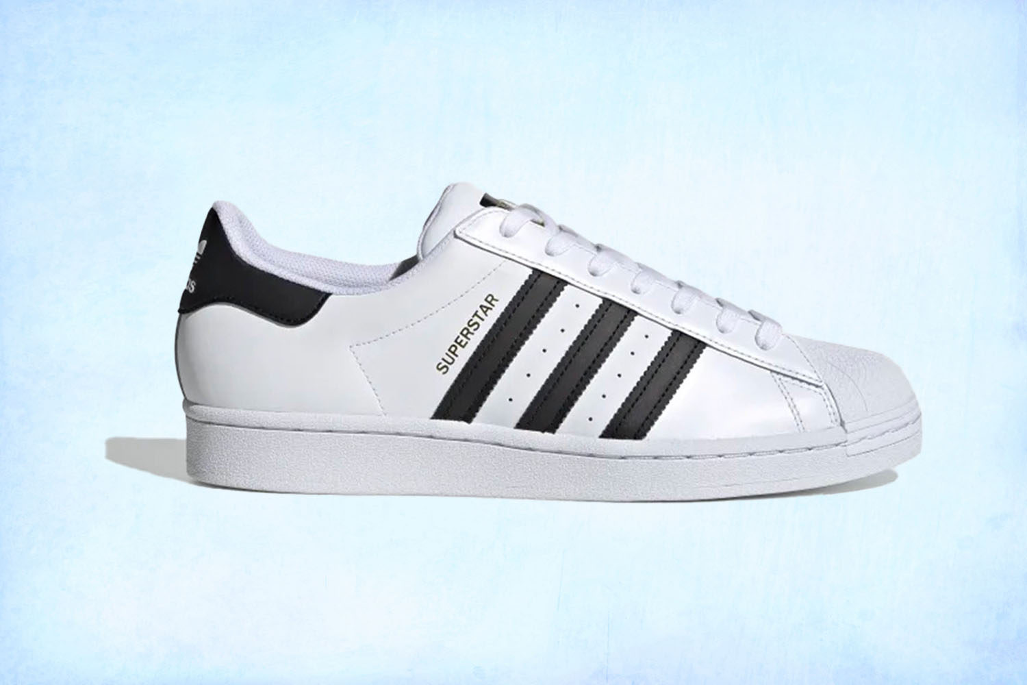 a white Adidas Superstar sneaker on a light blue background