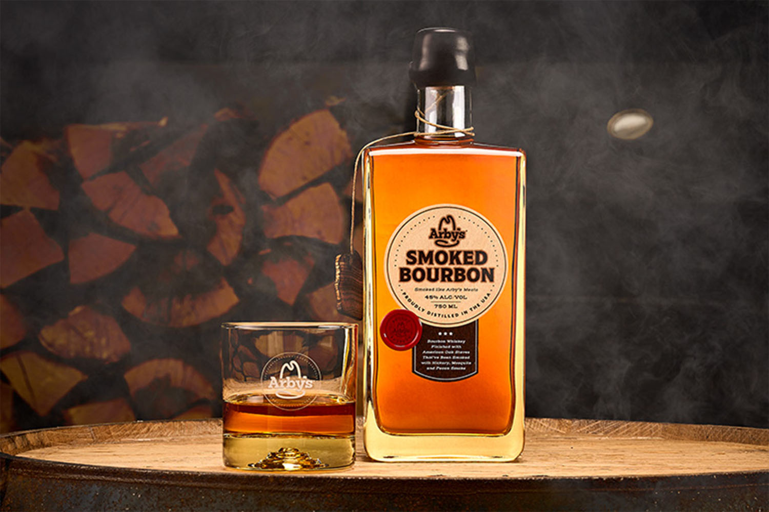 a bottle and glass of Arby's Smoked Bourbon on a wooden table