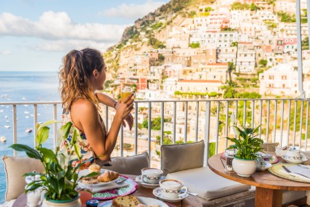 woman having breakfast in positano italy with orange juice and pastries