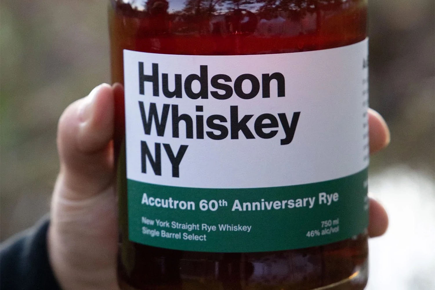 a hand holding a Hudson Whiskey bottle