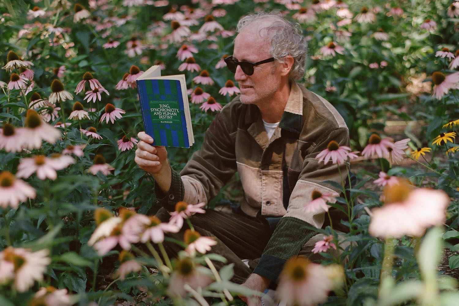 a model wearing J.Crew x Beams plus reading in a garden of flowers