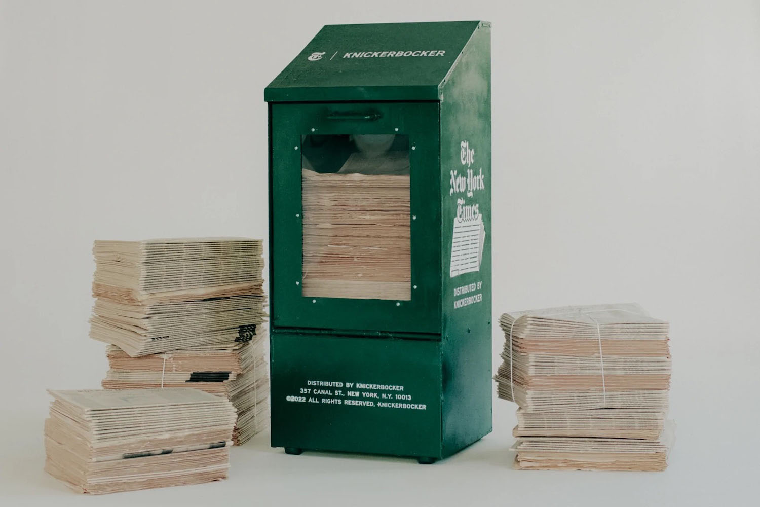 a news box and stacks of news papers on a grey background