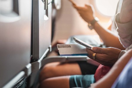 Man using a mobile phone in the middle seat of an airplane