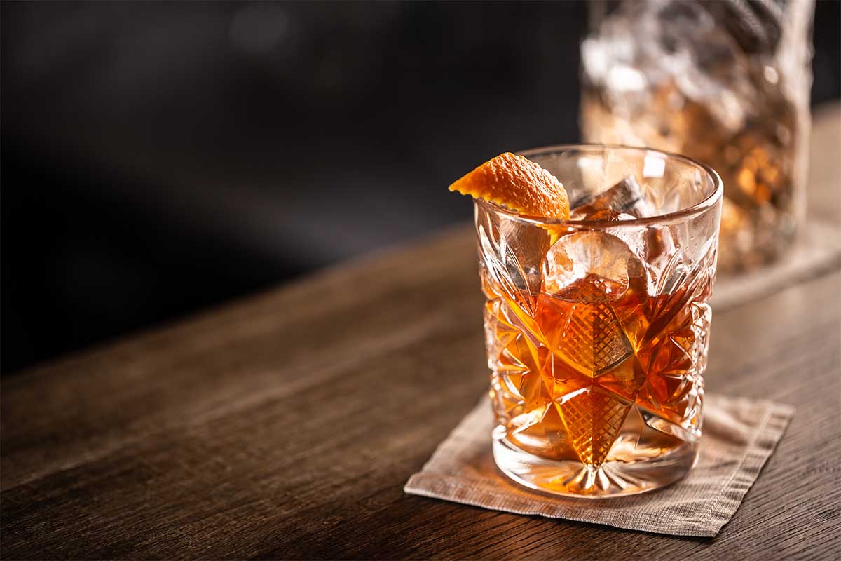 Old fashioned whiskey drink on ice with orange zest garnish. There are numerous ways to improve and perfect an Old Fashioned.