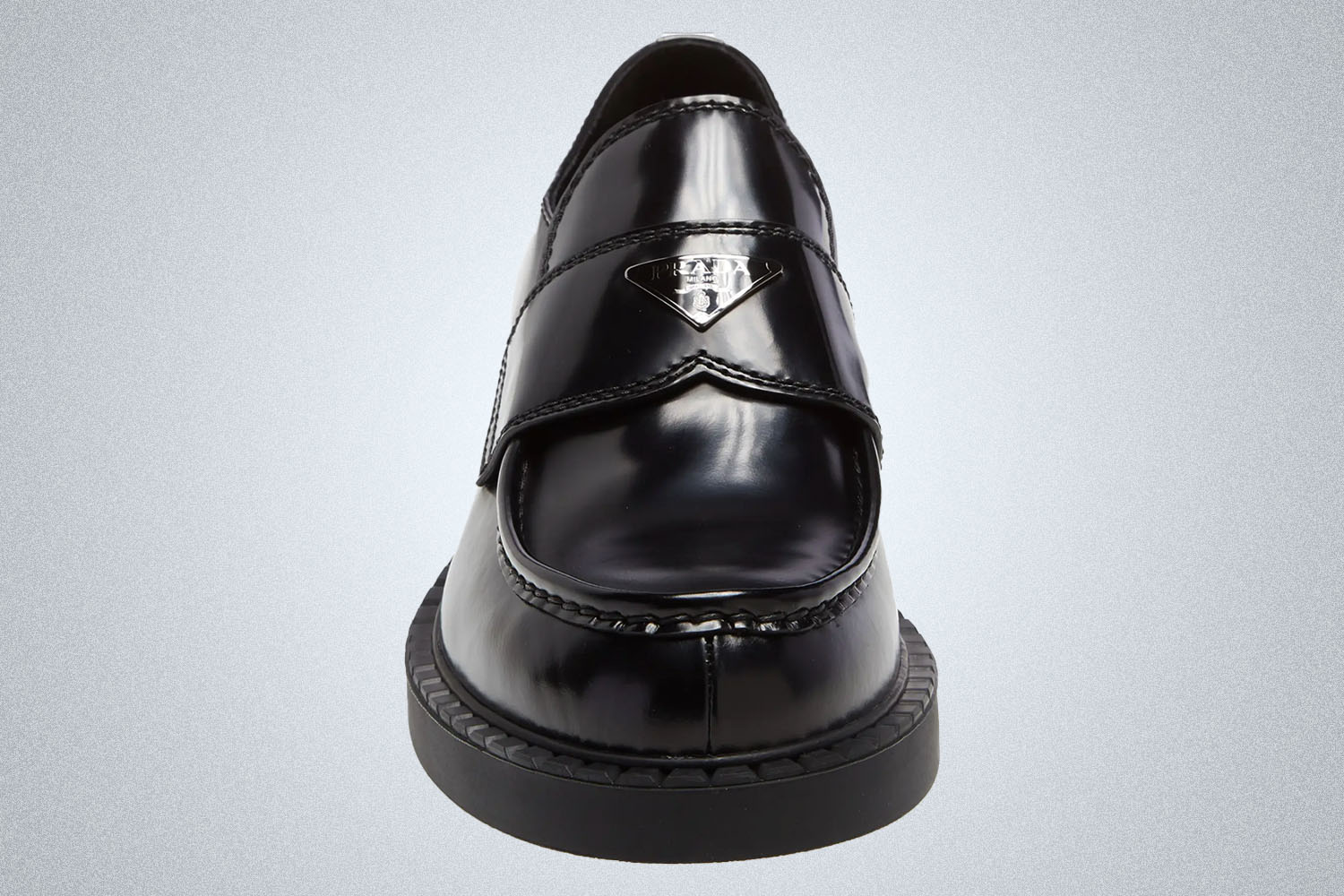 a black lug sole loafer from Prada on a grey background
