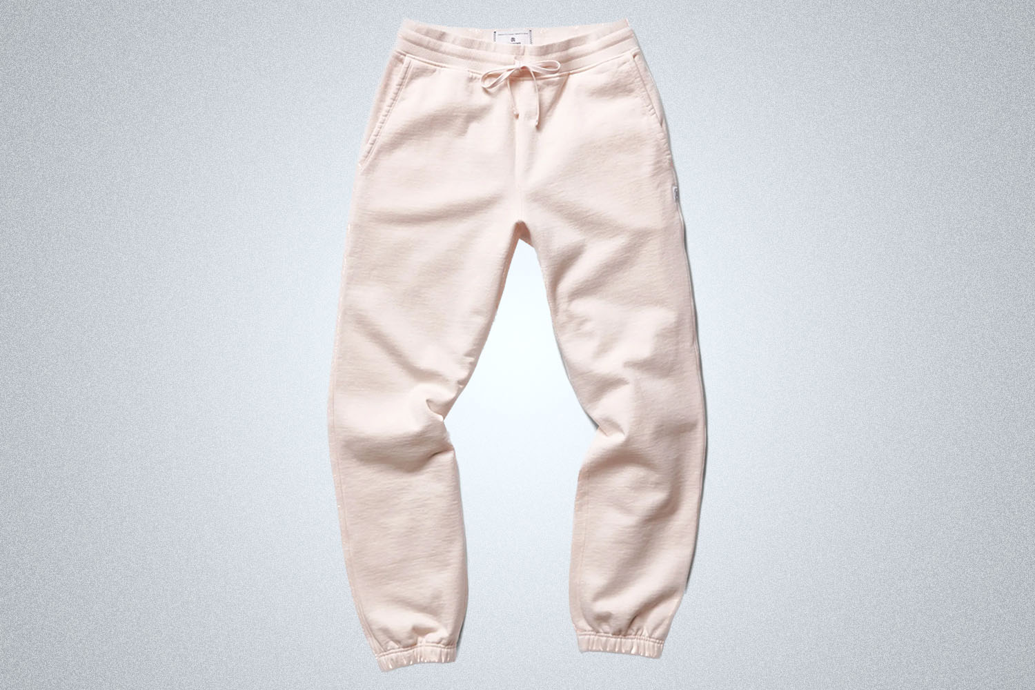 a pair of pink Reigning Champ sweatpants on a grey background