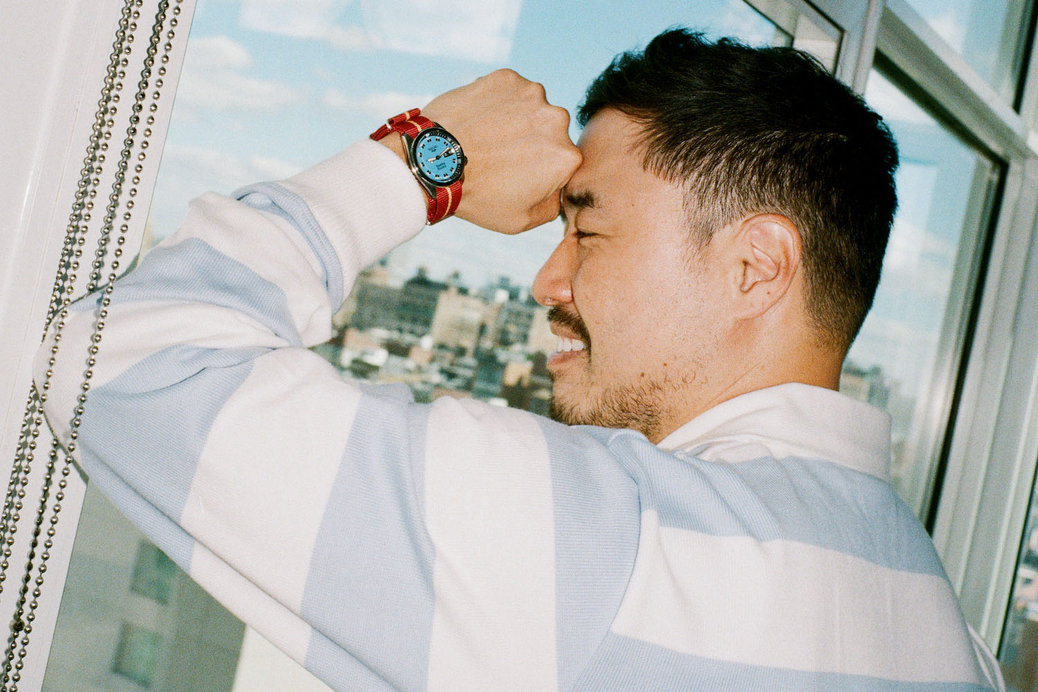 Actor Randall Park wearing the Rowing Blazers x Seiko watch standing against a window