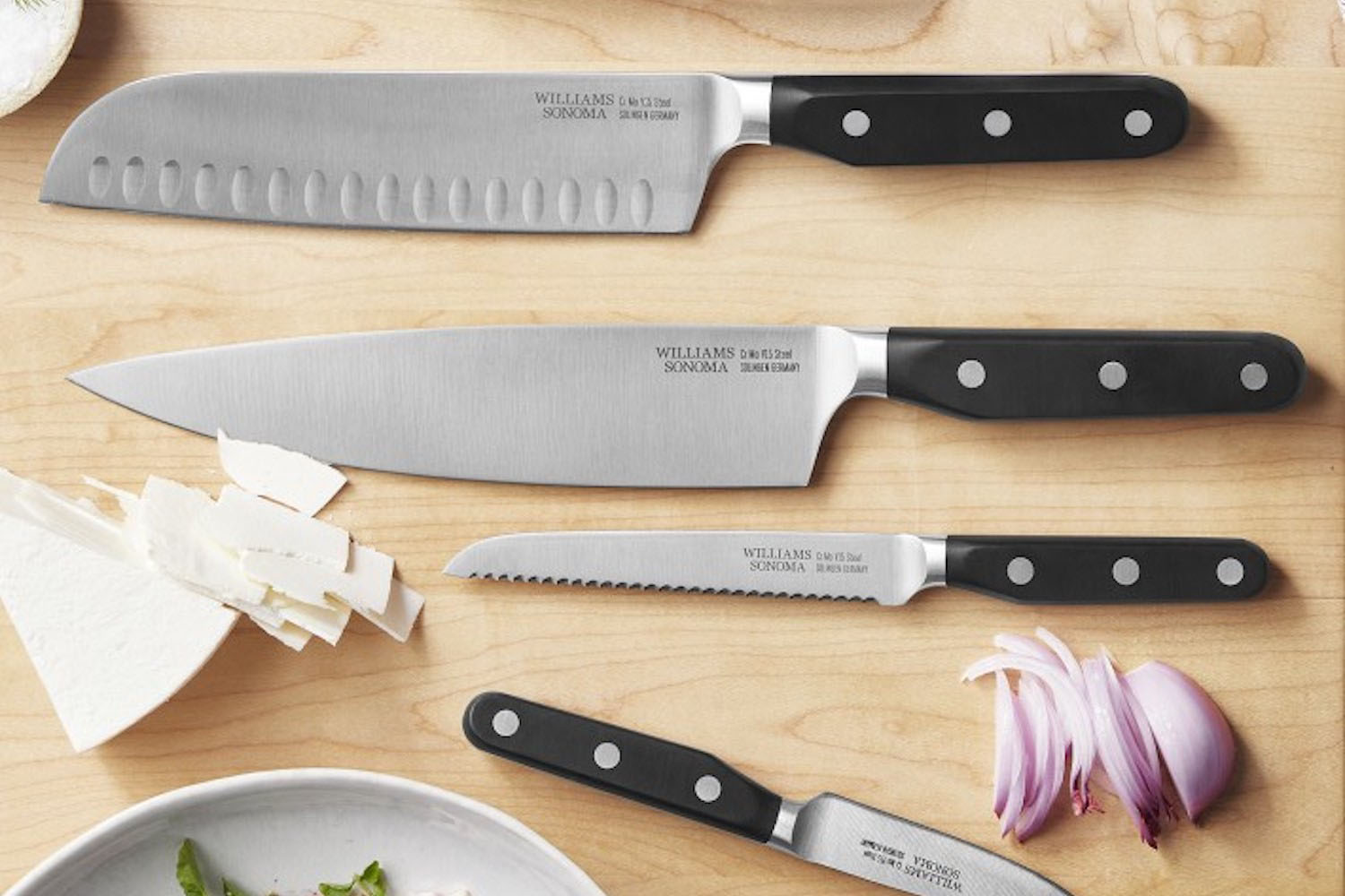 a collection of steel Williams Sonoma knives on a cutting board