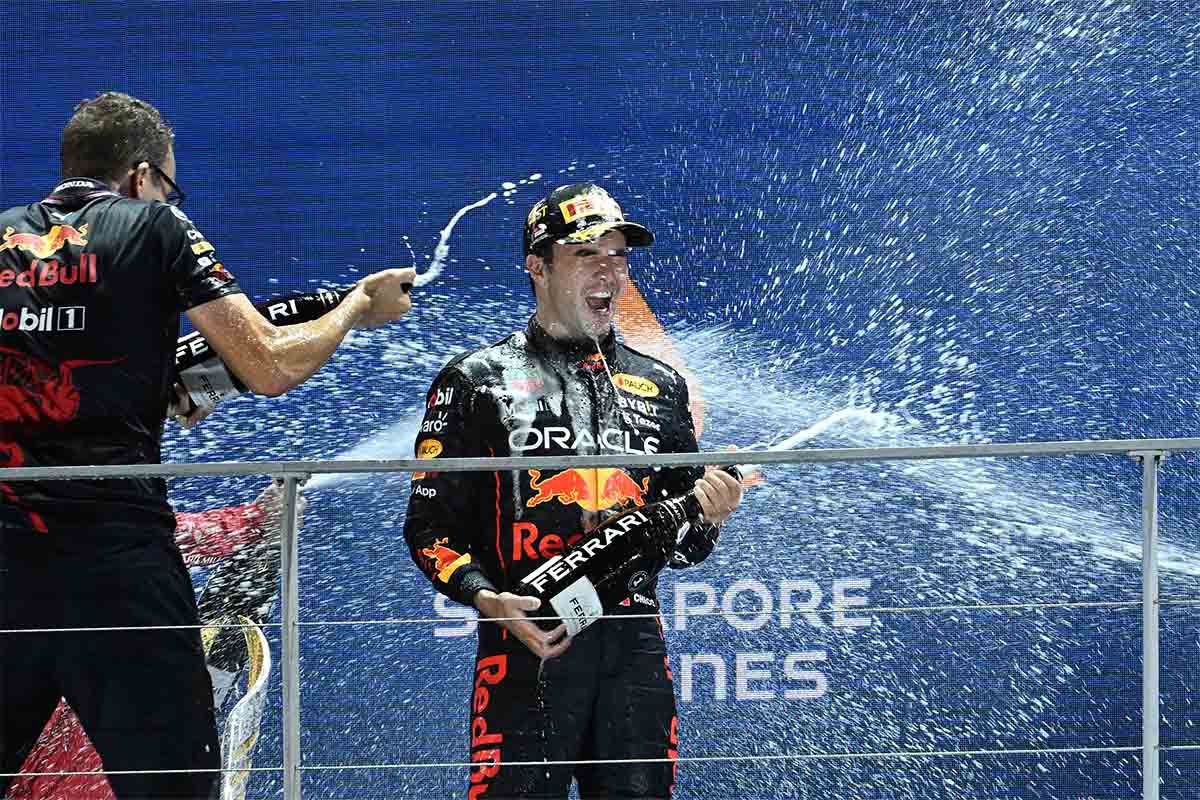 Winner Red Bull Racing's Mexican driver Sergio Perez (C) and Red Bull Racing's engineer Hugh Bird (L) celebrate with champagne on the podium after the Formula 1 Singapore Grand Prix night race at the Marina Bay Street Circuit in Singapore on October 2, 2022.