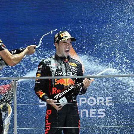 Winner Red Bull Racing's Mexican driver Sergio Perez (C) and Red Bull Racing's engineer Hugh Bird (L) celebrate with champagne on the podium after the Formula 1 Singapore Grand Prix night race at the Marina Bay Street Circuit in Singapore on October 2, 2022.