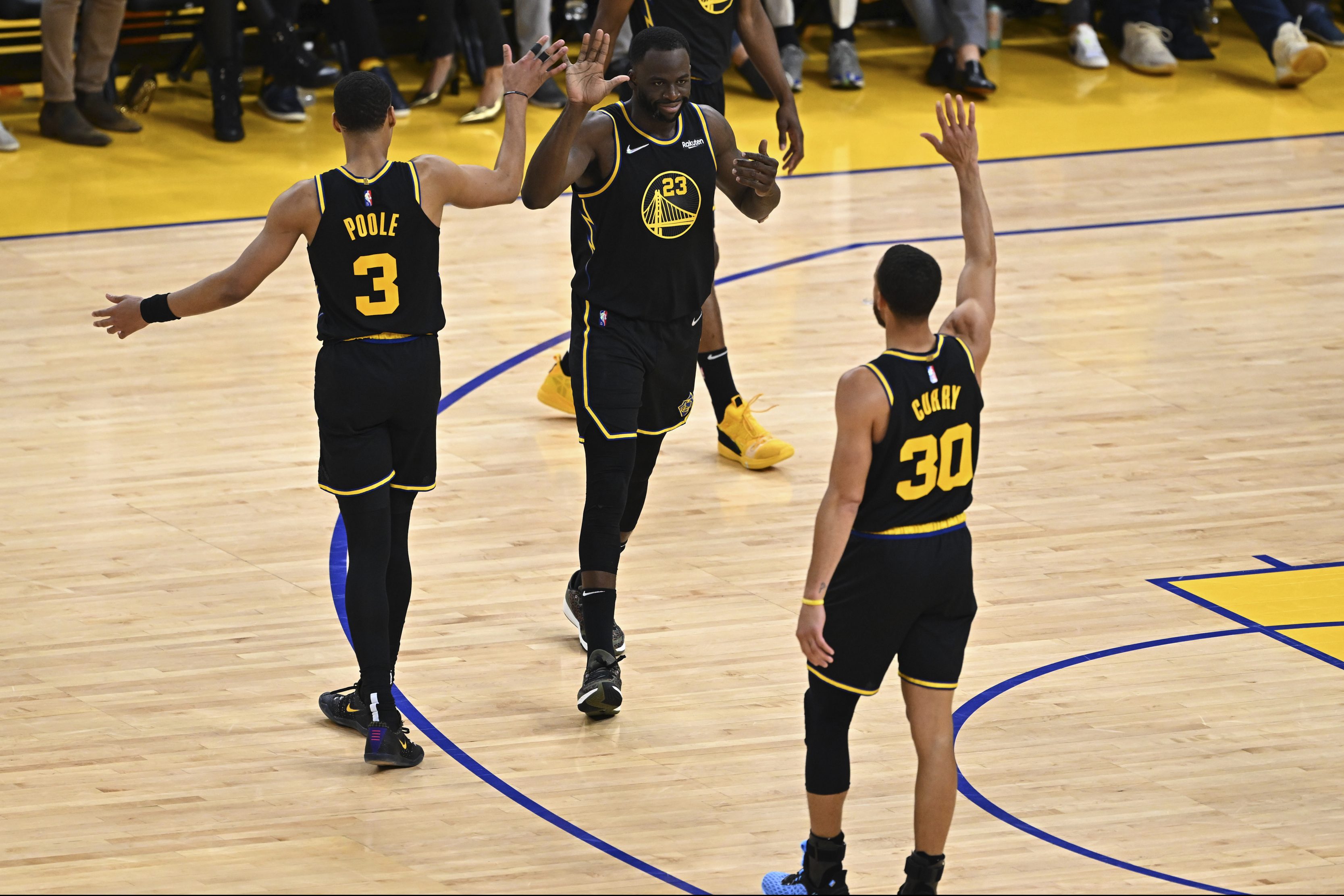 Draymond Green, Stephen Curry and Jordan Poole celebrate against the Dallas Mavericks.