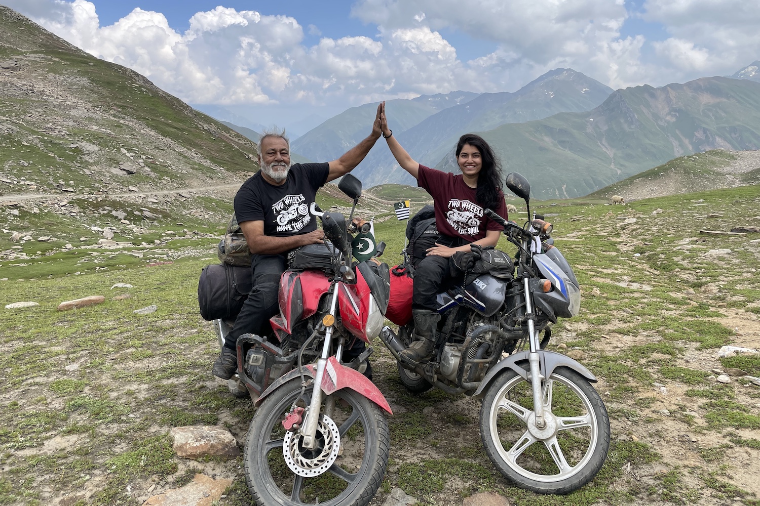 qazi and ghazal farooqi posing with their motorcycles in the mountains of pakistan
