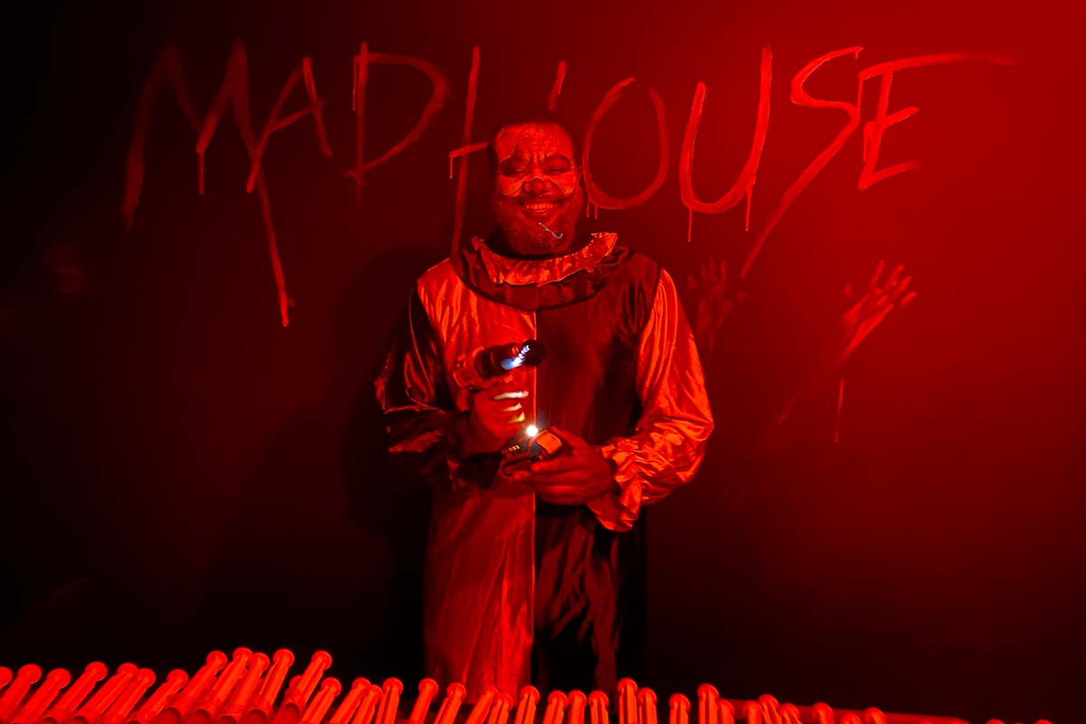 A clown at the Madhouse on Mulberry Street haunted house serving drinks