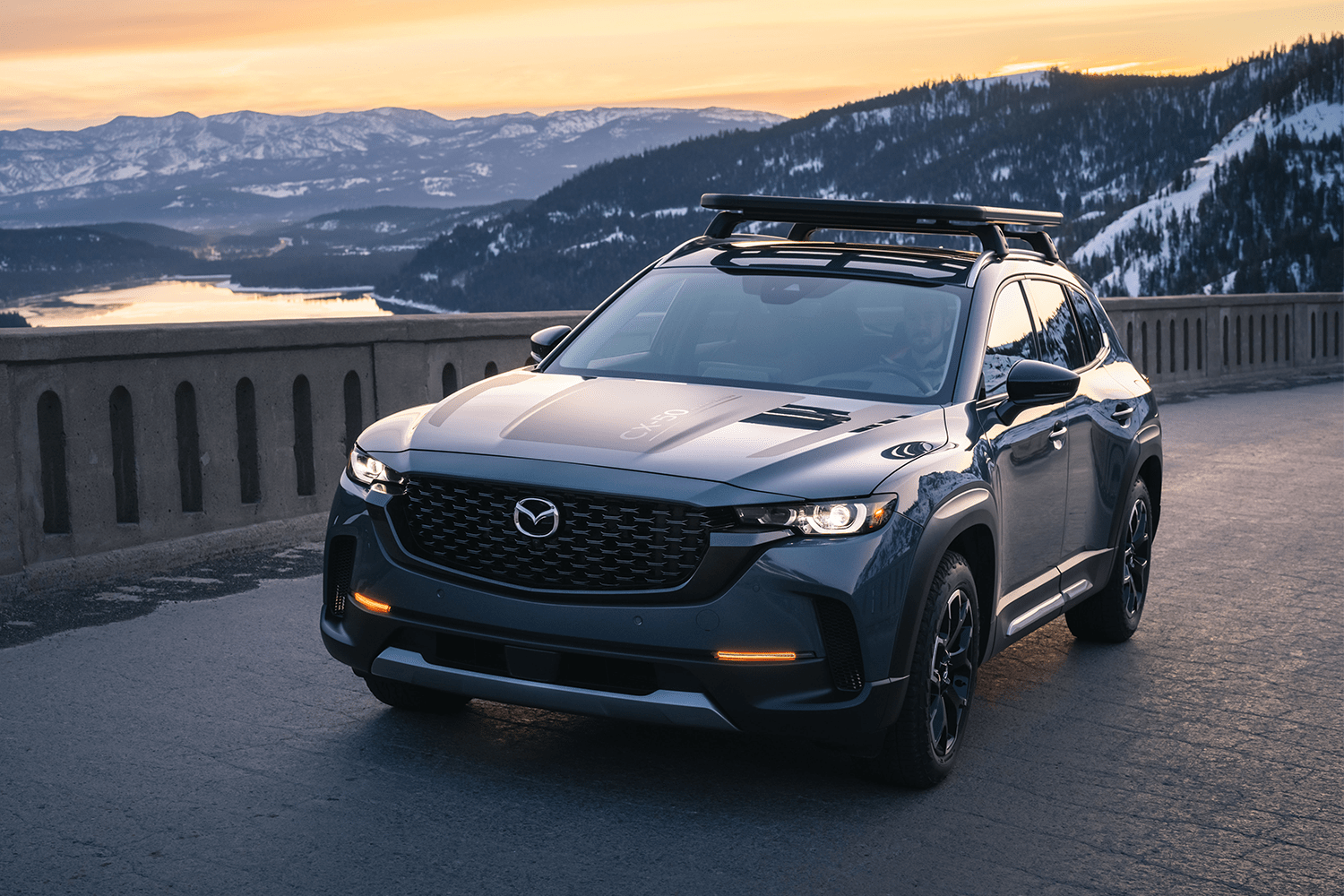 The new Mazda CX-50, an SUV that's similar to the Mazda CX-5, driving down the road at sunset