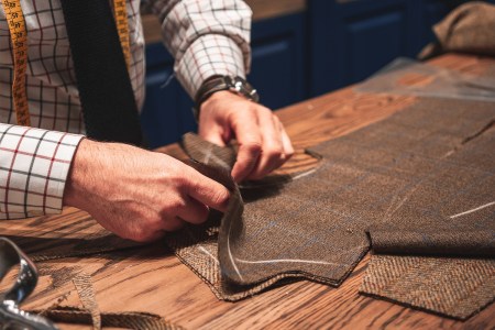 A tailor's hands close up stitching a piece of men's clothing