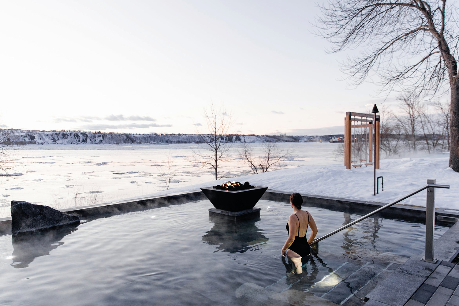 A woman stepping into a pool at Strøm Spa Nordique in Quebec City in the middle of winter