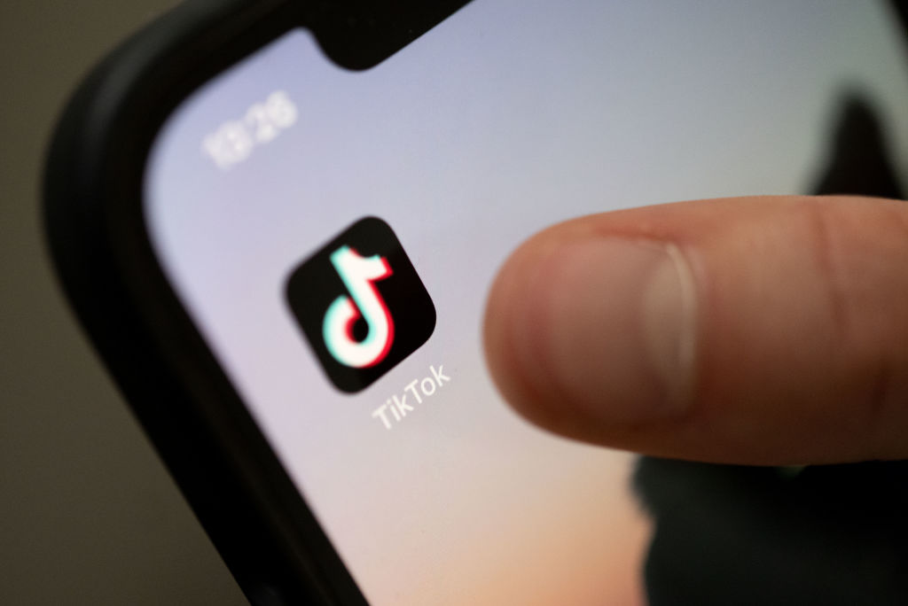 A finger reaching for the TikTok app on their smartphone screen